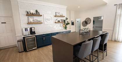 A kitchen with a long table and chairs.