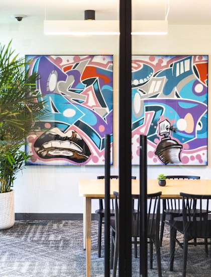 A room with a table and chairs in front of a wall with a mural.
