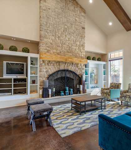 A living room with a stone fireplace and a blue couch.
