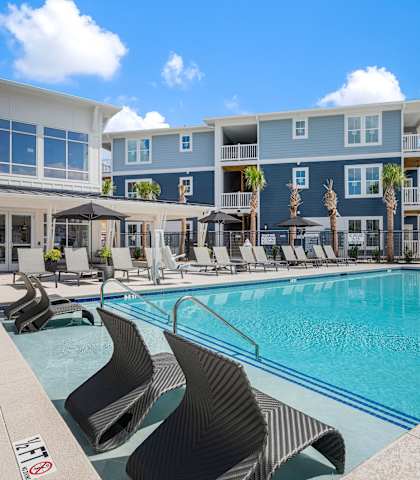 a swimming pool with lounge chairs in front of a building at Bristol at New Riverside, Bluffton, SC