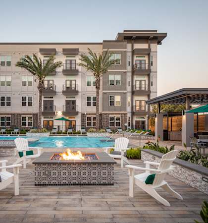A poolside area with a fire pit and lounge chairs.