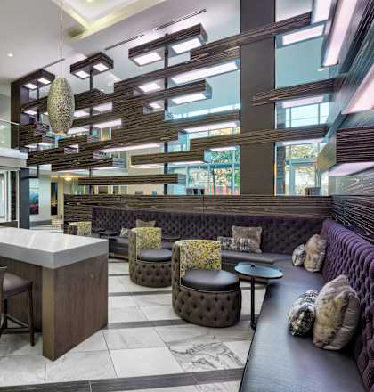 A modern bar with a long counter and a row of stools.