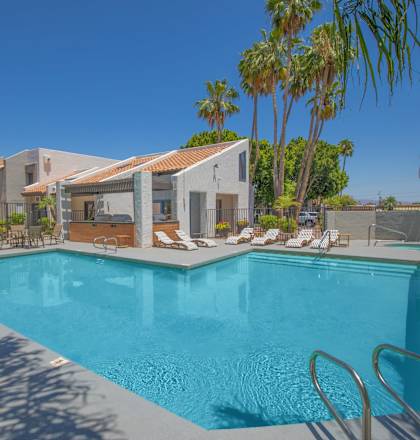 a swimming pool with chairs around it and a house in the background
