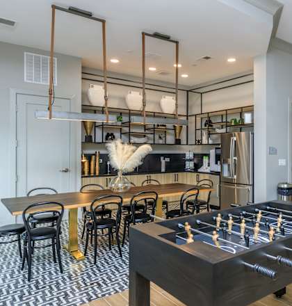 A foosball table is in the middle of a room with a bar in the background.