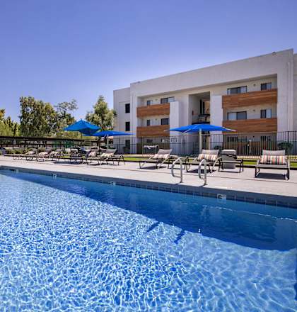 a swimming pool with chairs and umbrellas next to a building