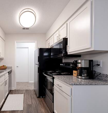 A kitchen with black appliances and white cabinets at Gramercy Apartments, Carmel, 46032