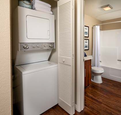 A small bathroom with a toilet, sink, and a washer and dryer.