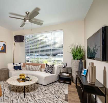 A living room with a white couch, a yellow chair, and a black television.