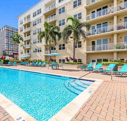 A large swimming pool surrounded by a brick patio and lounge chairs.