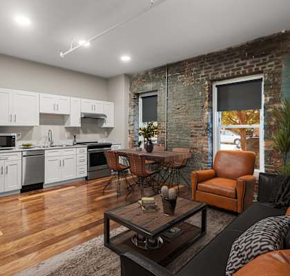 A modern kitchen with wooden floors and a brick wall.