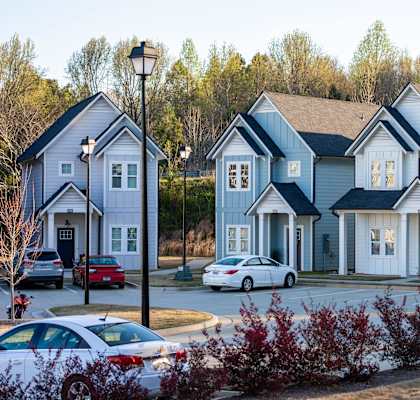 A row of houses with cars parked in front.