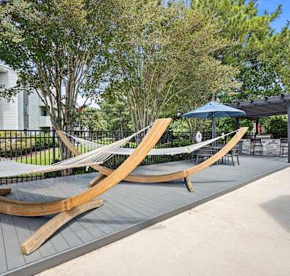 two hammocks on a patio with umbrellas and trees