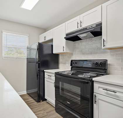 an empty kitchen with white cabinets and black appliances
