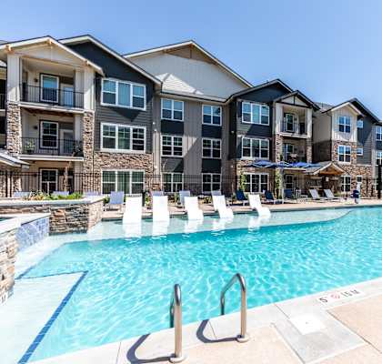 A large swimming pool in front of apartment buildings.