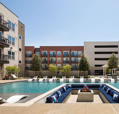 A large swimming pool with lounge chairs and a fountain in the middle.