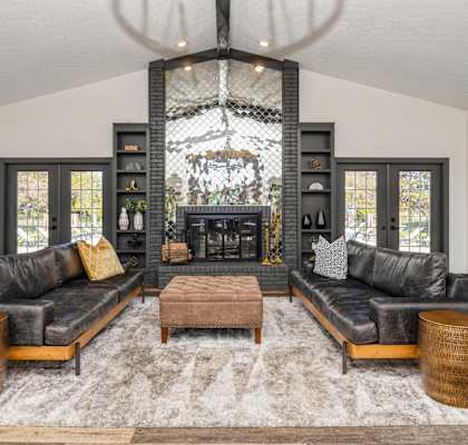 A modern living room with a black leather couch, a wooden coffee table, and a chandelier. at Karric Place of Dublin Apartments, Ohio, 43016