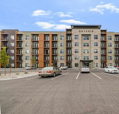 A parking lot in front of a multi-story apartment building named Reverie.