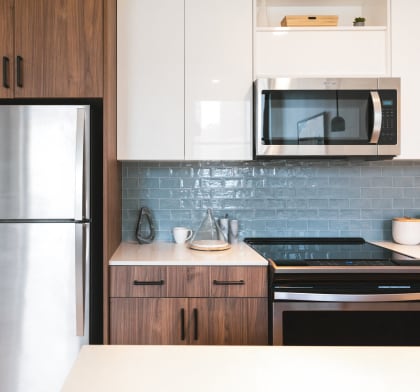 a modern kitchen with stainless steel appliances and white cabinets at The Press/321, Detroit MI