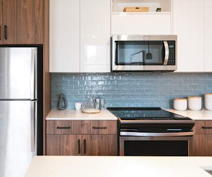 a modern kitchen with stainless steel appliances and white cabinets at The Press/321, Detroit MI
