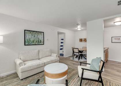 A living room with a white couch and a painting on the wall.