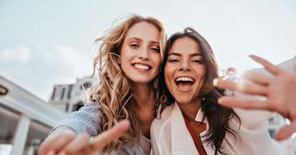 Two women are making a peace sign with their hands.