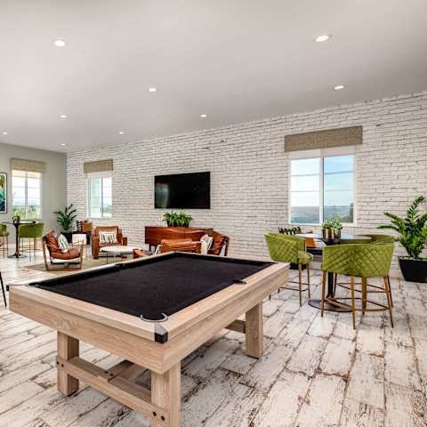 A pool table is in the middle of a room with a bar and a television. at San Carlo Townhomes Apartments, Highland, CA