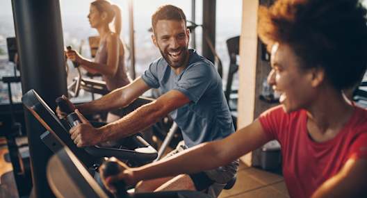 a man and a woman riding on exercise bikes in a gym