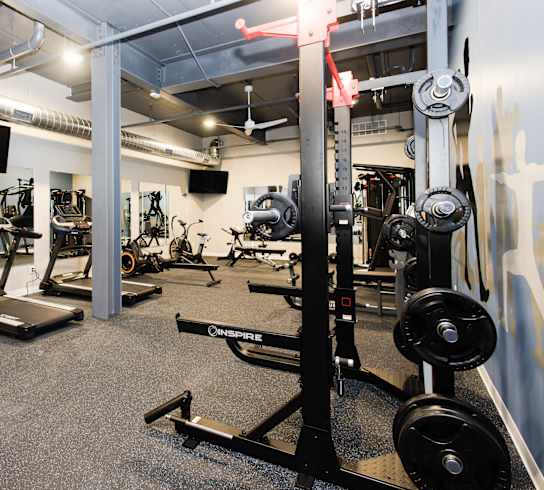 a gym with weights and other exercise equipment in a building with white walls