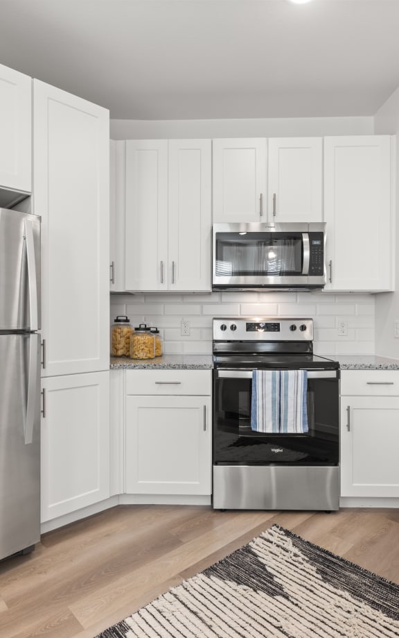 a white kitchen with stainless steel appliances and white cabinets