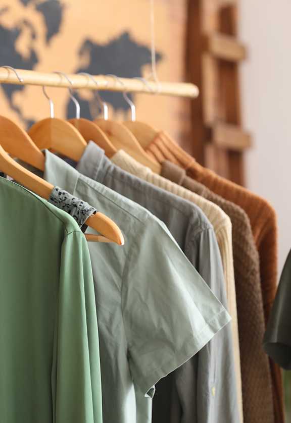 A row of shirts in various colors are hanging on a rack.
