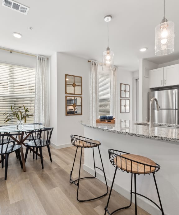 a kitchen with a bar and a dining area with a table and chairs
