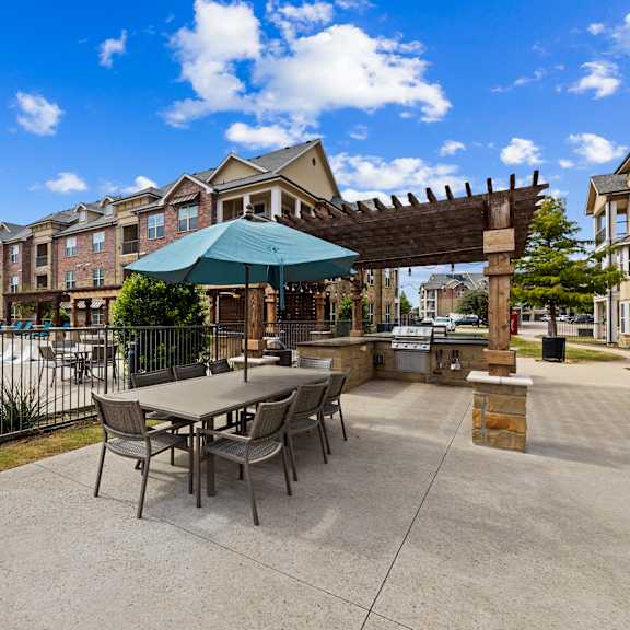 Poolside patio seating area at Auberge of Burleson apartments in Burleson TX.