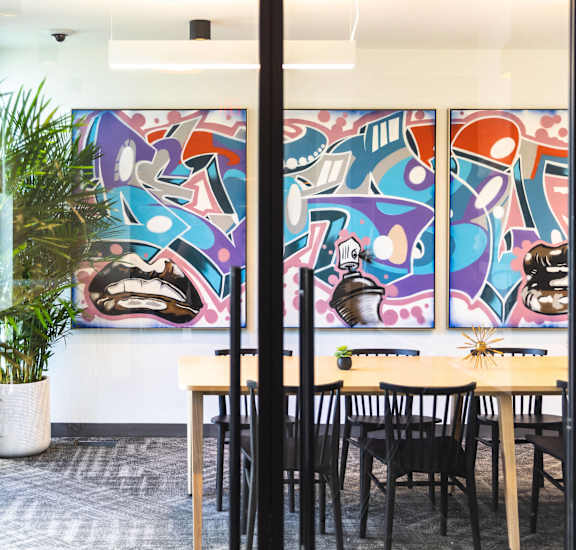 A room with a table and chairs in front of a wall with a mural.