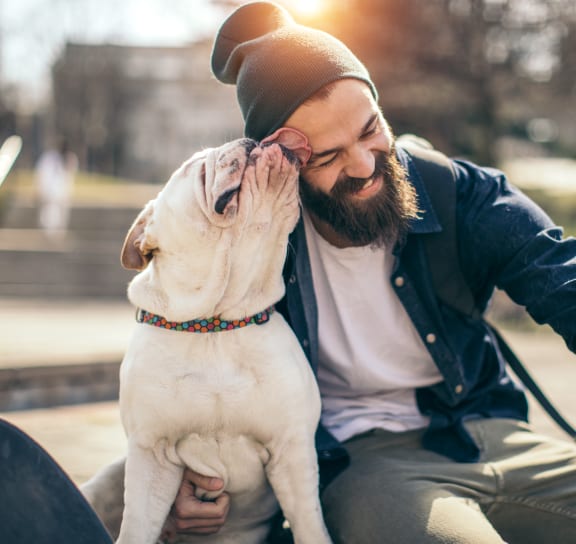 a man sitting on a bench with his dog at Windmill Lakes Apartments, Holland, 49424