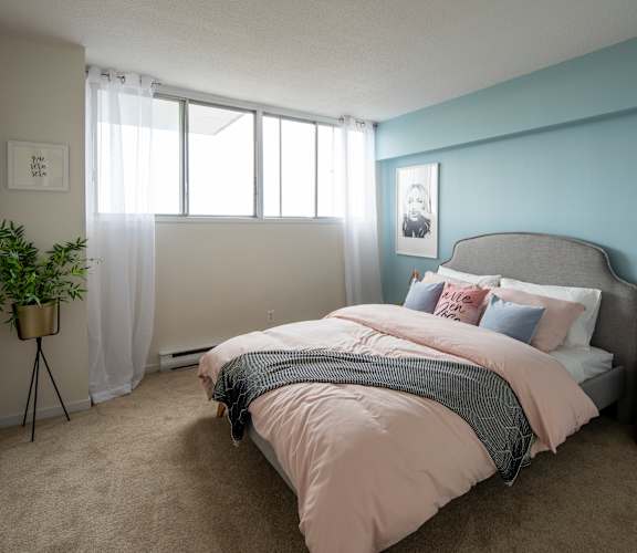 A bedroom with a large bed and a potted plant.