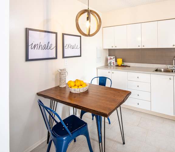 A kitchen with a table and chairs and a fridge.