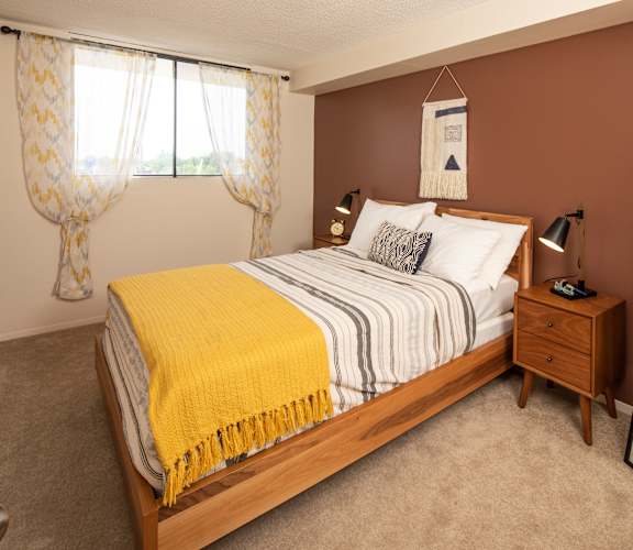 A bedroom with a bed, nightstand, and a mirror.
