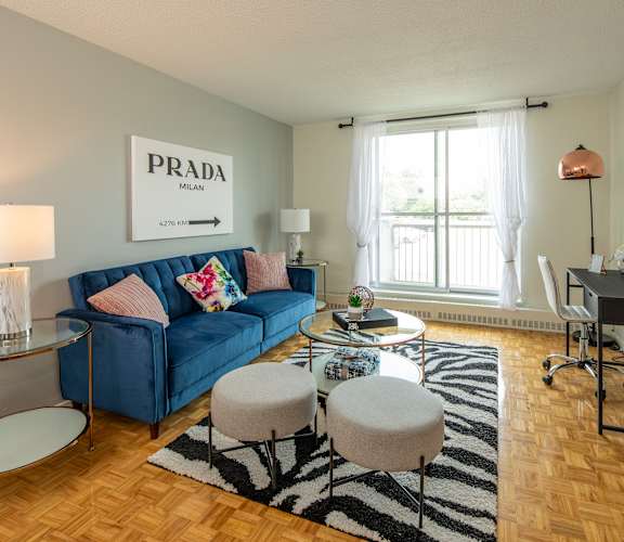 A living room with a blue sofa and a Prada sign on the wall.