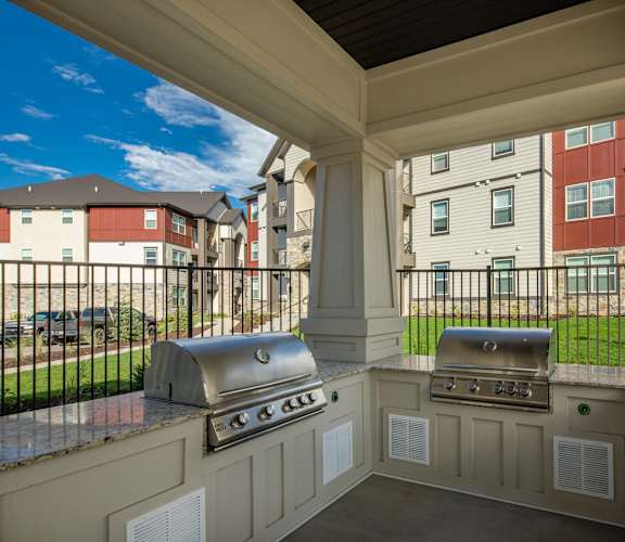 a covered outdoor kitchen with two stainless steel grills