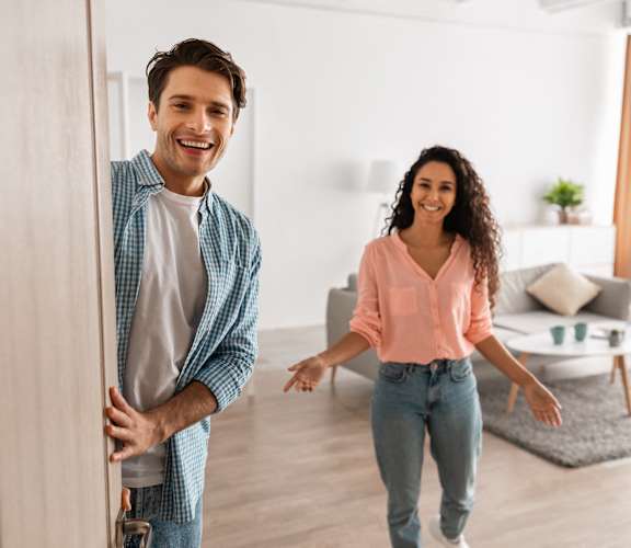 a man and woman walking through a door into a living room