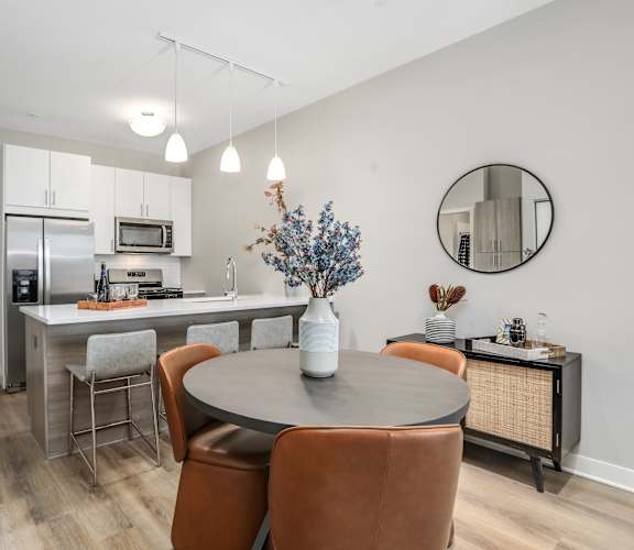 a dining area with a table and chairs and a kitchen with stainless steel appliances at Beekman on Broadway, Ann Arbor, MI