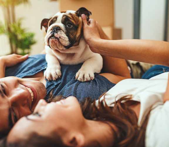 A person is lying down with a dog on their shoulder.