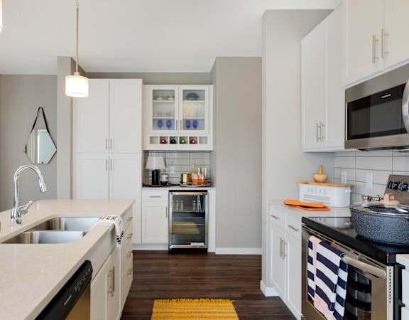 A kitchen with white cabinets and a yellow rug on the floor.