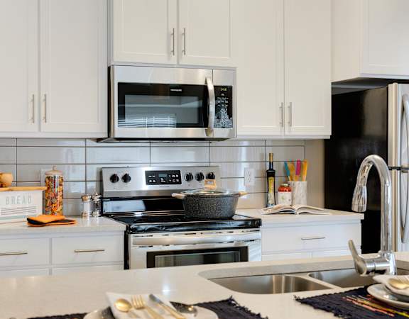 A modern kitchen with white cabinets and stainless steel appliances.