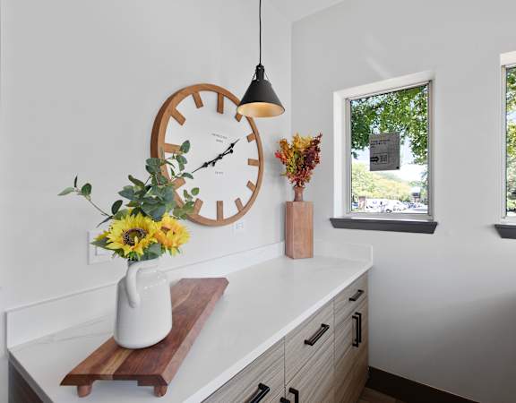 a kitchen counter with a clock and a vase of flowers