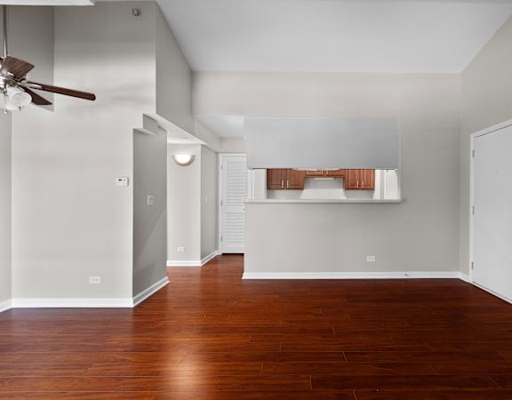 an empty living room with wood floors and a ceiling fan