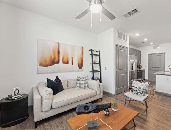 A living room with a white couch and a painting on the wall.
