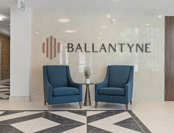 Two blue chairs are placed in front of a wall with the word "BALLANTYNE" on it.
