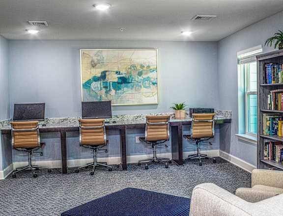 A room with a blue rug, a white couch, a bookshelf, and a painting on the wall.
