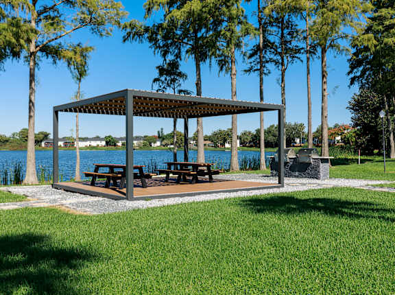 a pavilion with benches in a park next to a lake